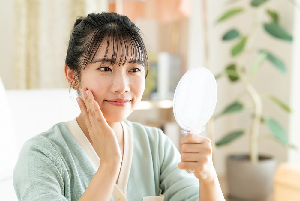 鏡で肌の状態を確認する女性。画像はイメージ。（写真：Adobe Stock）