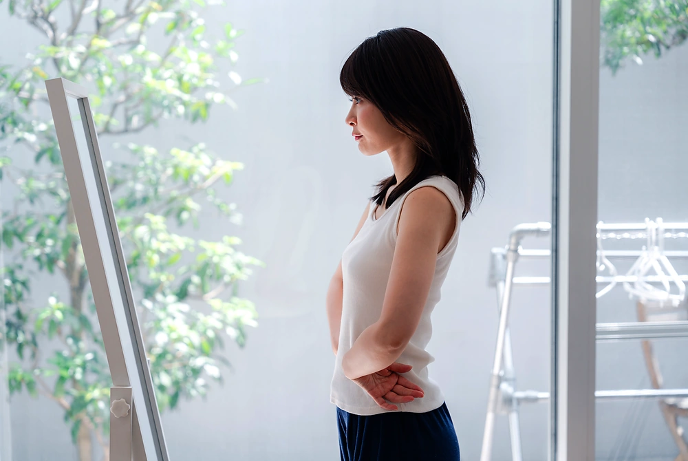 鏡で体型の変化を確認する女性。画像はイメージ。(写真:Adobe Stock)