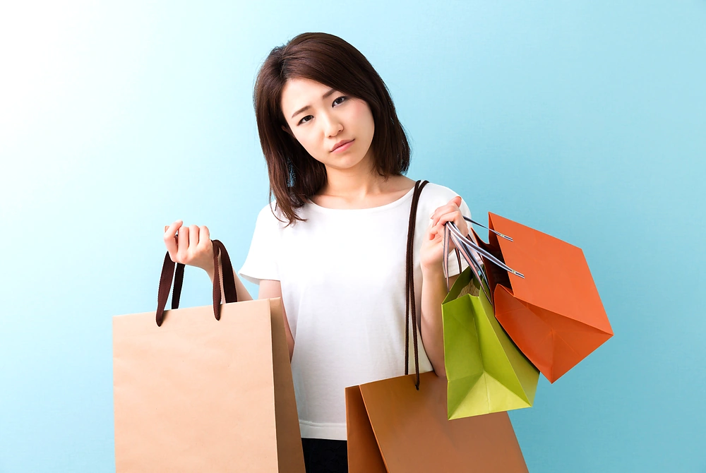 買い物や消費行動に悩む女性。画像はイメージ。（写真：Adobe Stock）