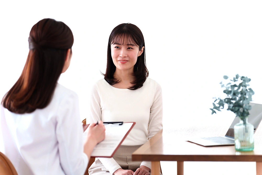 女性が医療者と向き合い、診療や治療について相談している様子。