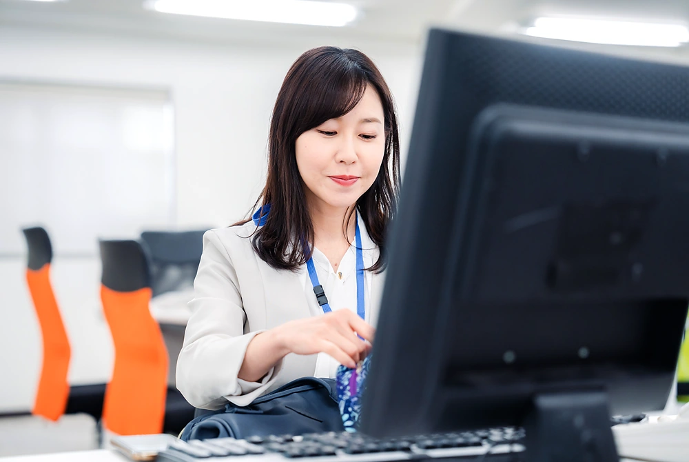 空調の効いたオフィスでパソコン作業をする女性。