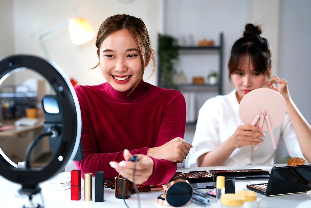 リングライトの前でメイクやスキンケアの発信をする女性たち。