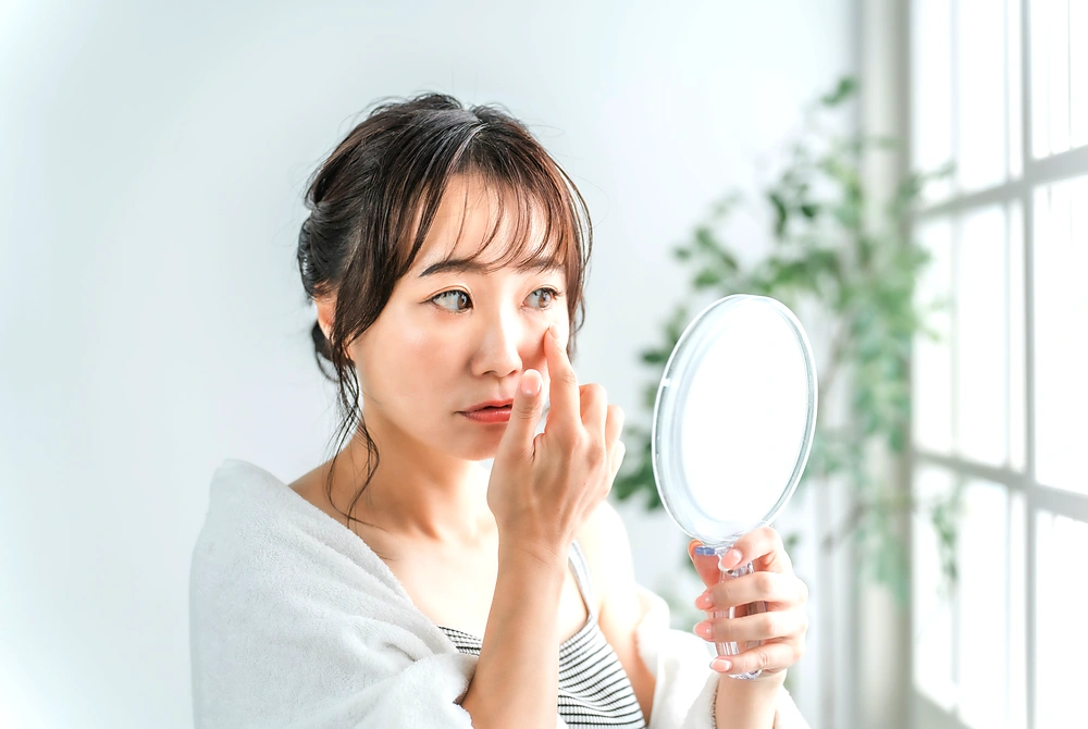鏡を見ながら目元の状態を確認する女性。