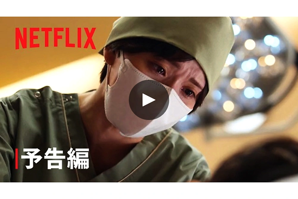 Netflixシリーズ『ダウンタイム』の予告編で、マスク姿の医師が施術中の相手に向き合う場面。