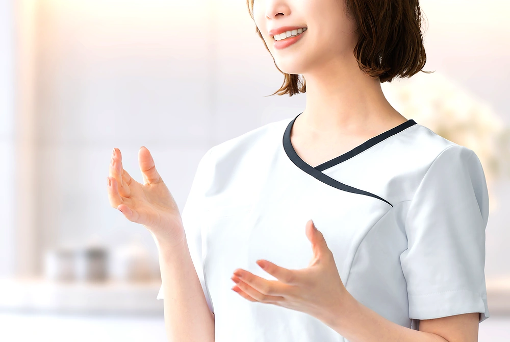美容クリニックのスタッフが、手ぶりを交えながら利用者に説明している。