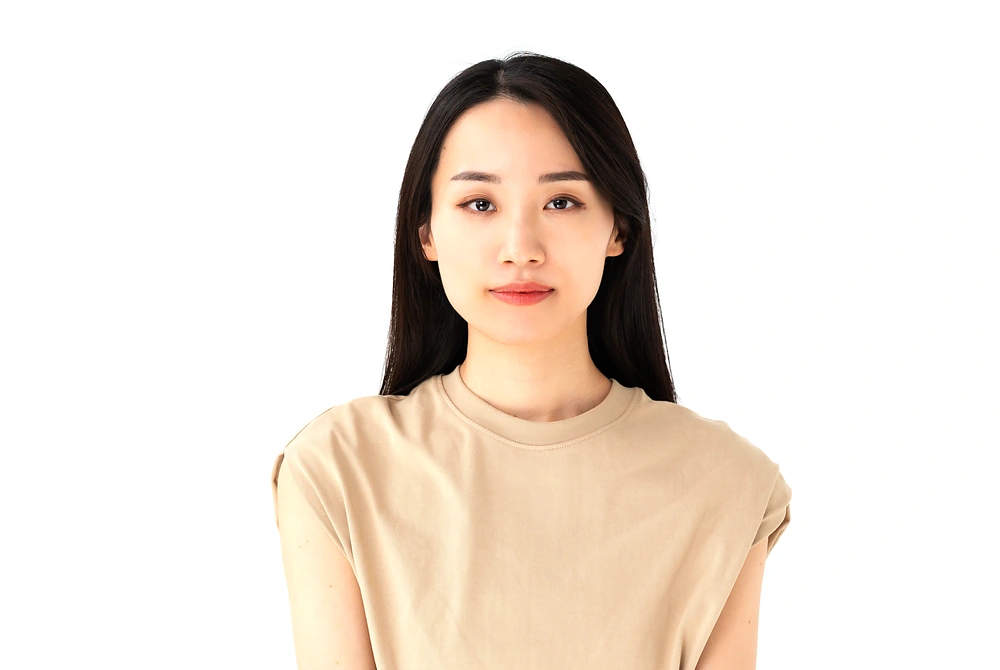 白い背景の前で正面を向く女性の顔。