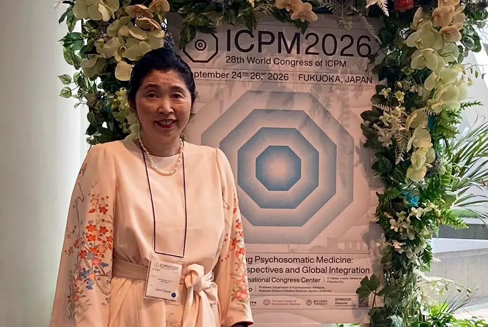 ICPM2026の会場でポスターの前に立つ福田ゆみ氏。