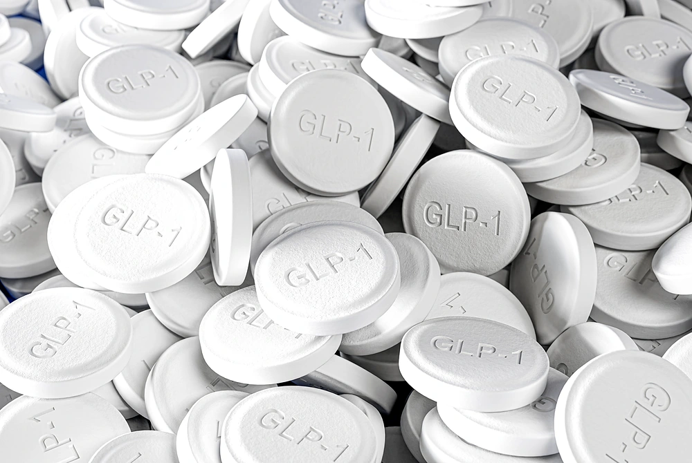 GLP-1と刻まれた白い錠剤が多数重なっている。