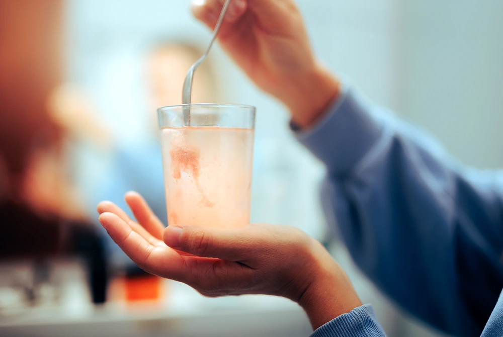 コップの中の粉末飲料をスプーンでかき混ぜる手元。