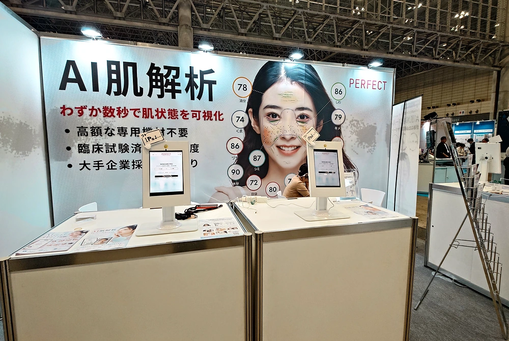 PERFECTのAI肌解析サービスを紹介する展示ブース。顔画像の肌状態を数値化したパネルとタブレット端末が並ぶ。