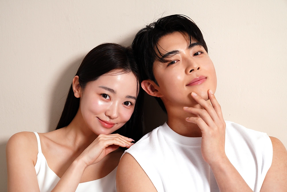 顔に手を添える若い男女。皮膚の再生や肌の状態に見られる男女の違いをイメージした写真。