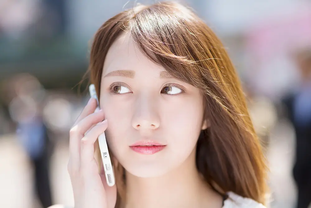 スマートフォンで通話する若い女性。画像はイメージ。（写真：Adobe Stock）