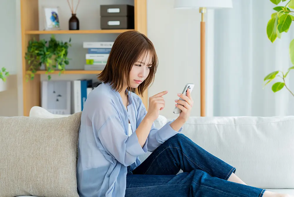 スマートフォンを操作する若い女性。画像はイメージ。（写真：Adobe Stock）
